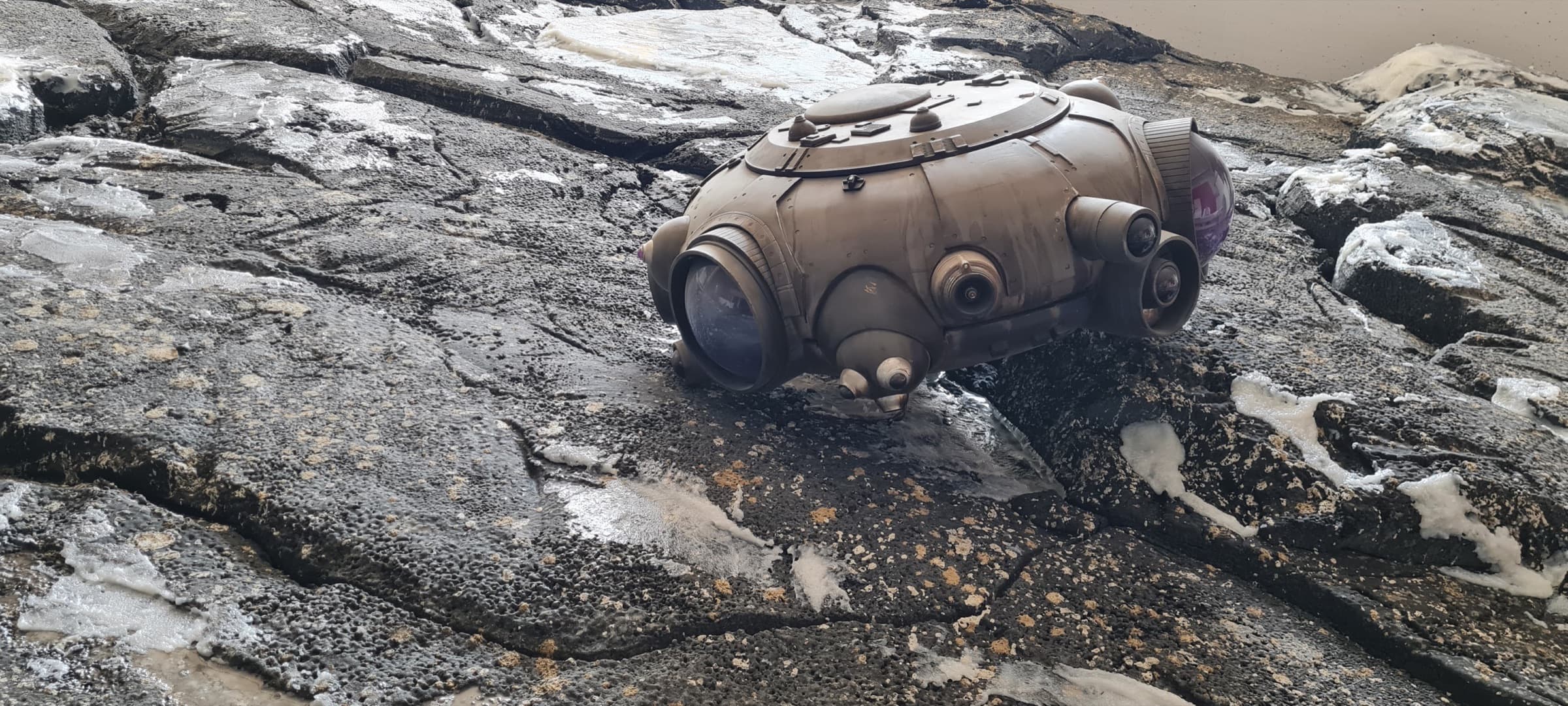 Scenografia di ScenoLab 27: una capsula spaziale retrofuturista adagiata su un terreno di roccia lavica